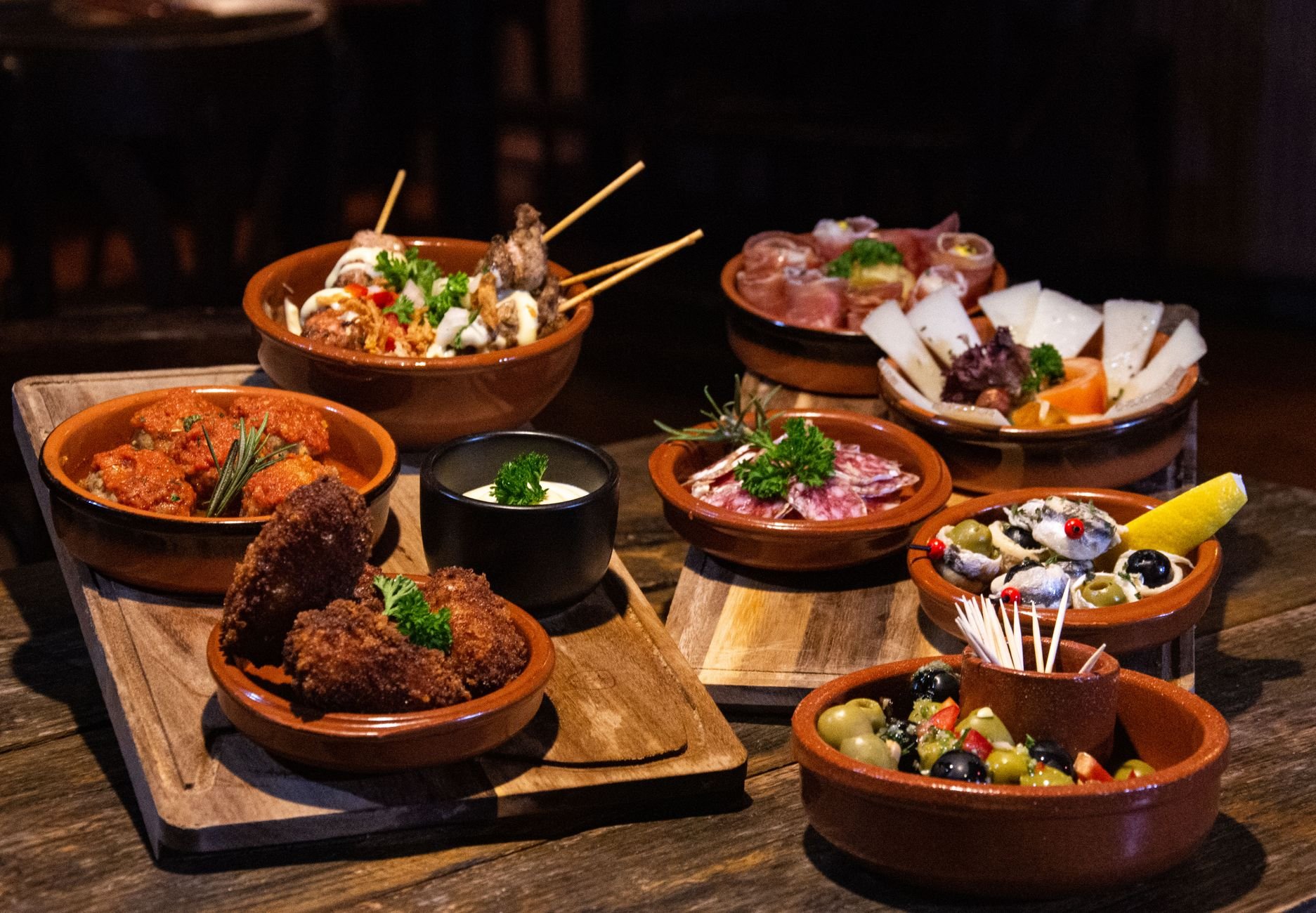 Spanish tapas served on a rustic wooden table.