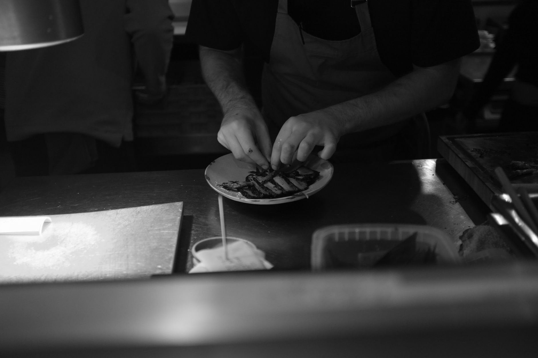 A chef plating food in a dimly lit kitchen.
