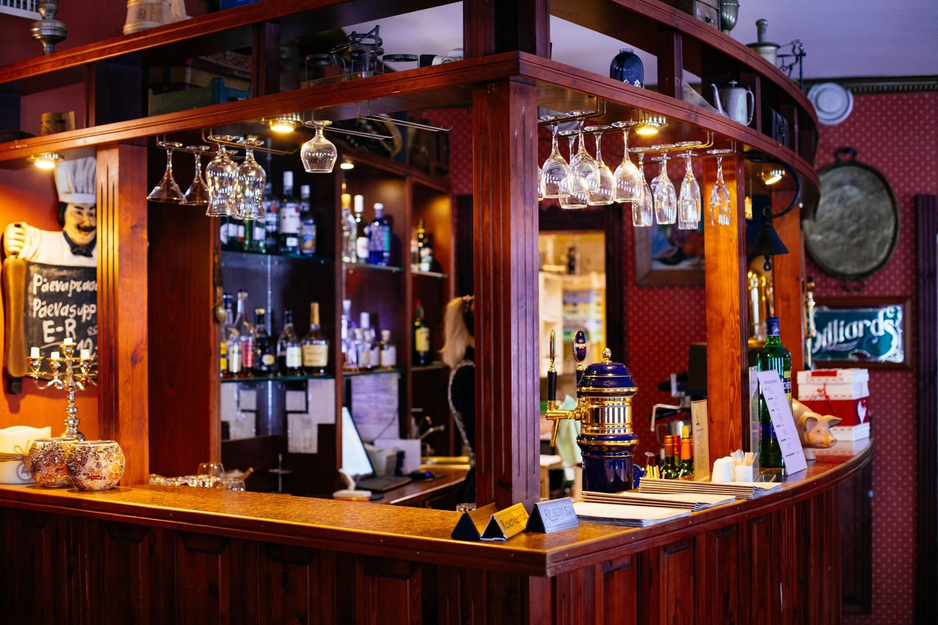Wooden bar with wine glasses hanging overhead.